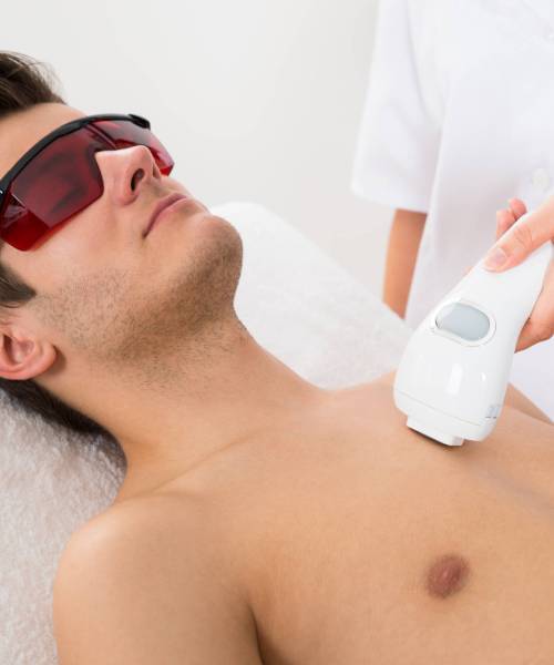 Close-up Of Female Worker Giving Man Laser Epilation On Chest In Salon